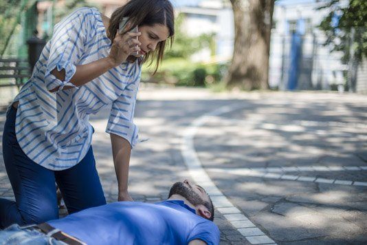 Lady calling emergency services to help collapsed man